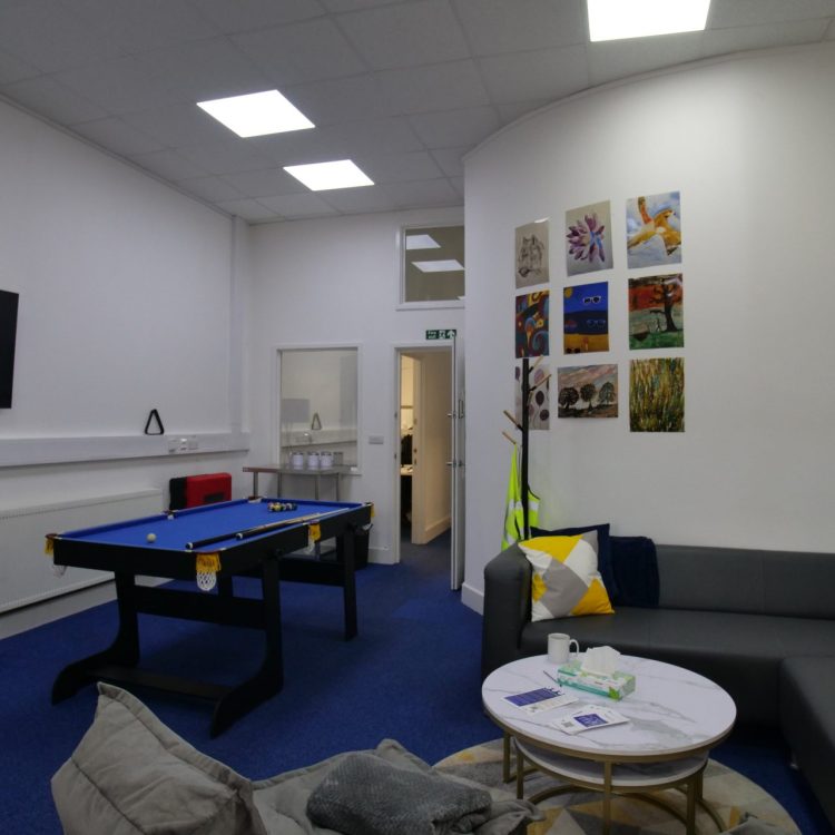 the photo shows an inside room from our Hatfield crisis cafe, including a television, sofa, kitchen area and chairs